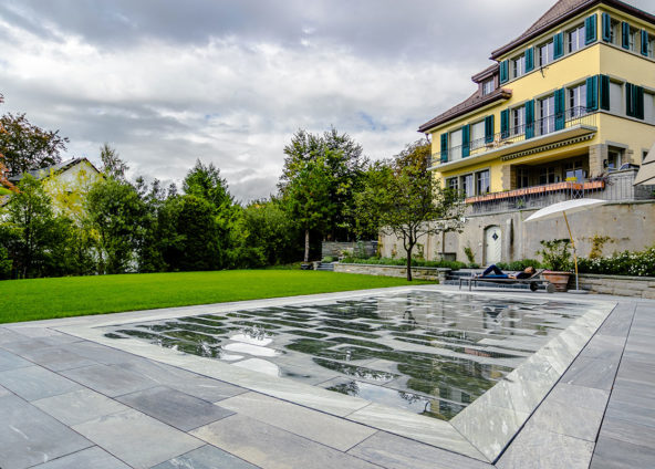 Ein gelbes Haus mit schönem Garten und einem Hubboden Pool, welcher hochgefahren ist von Flusspool.